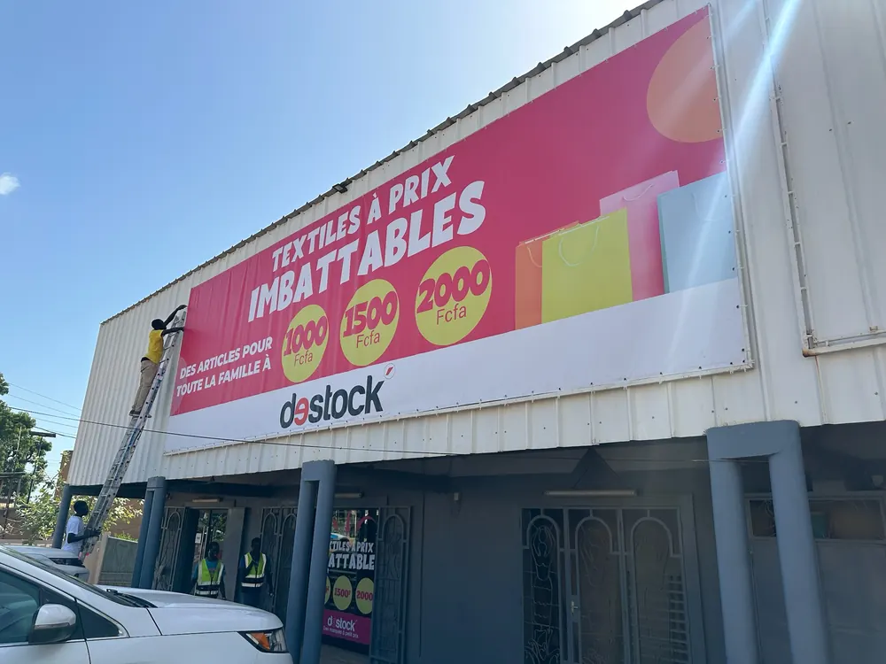 Bâche publicitaire grand format sur façade de magasin à Mbour